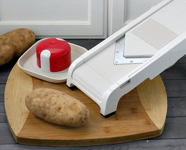 potato on a cutting board with a mandolin