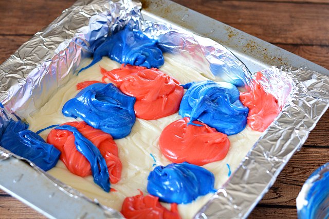 white vanilla fudge in a square pan with glops of blue and red fudge on top