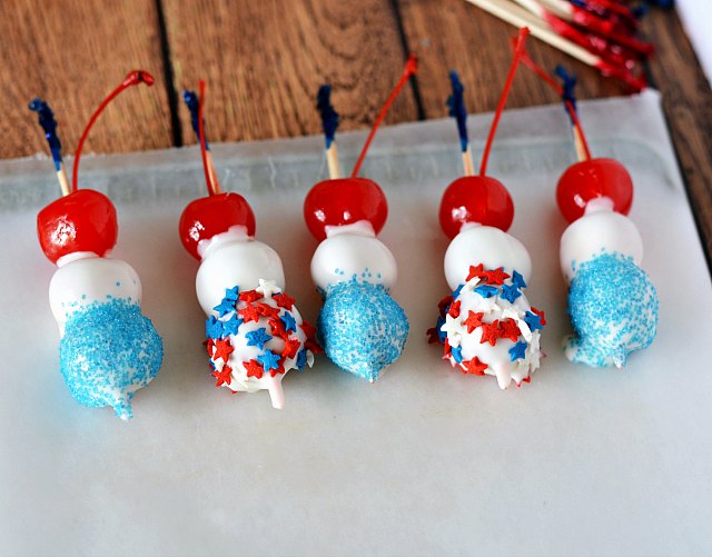 Maraschino cherries dipped in white chocolate with sprinkles on them.