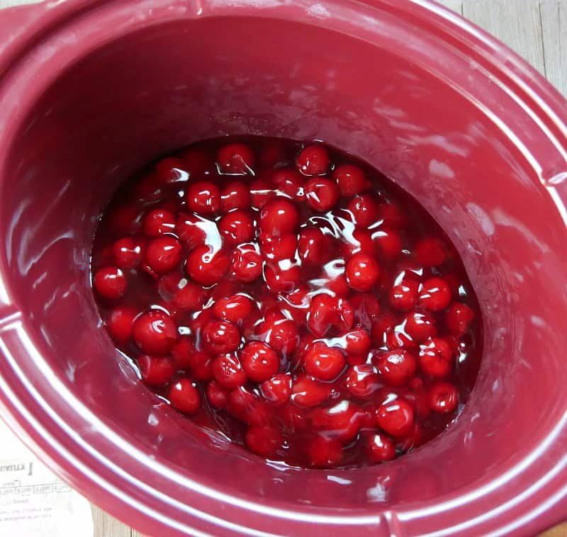 Cherry pie filling in an oval red slow cooker crock.