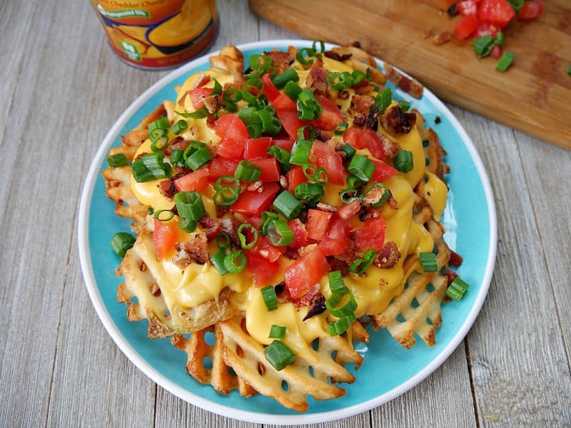 plate of Irish nachos recipe with waffle fries, nacho cheese, bacon, green onions and diced tomatoes 