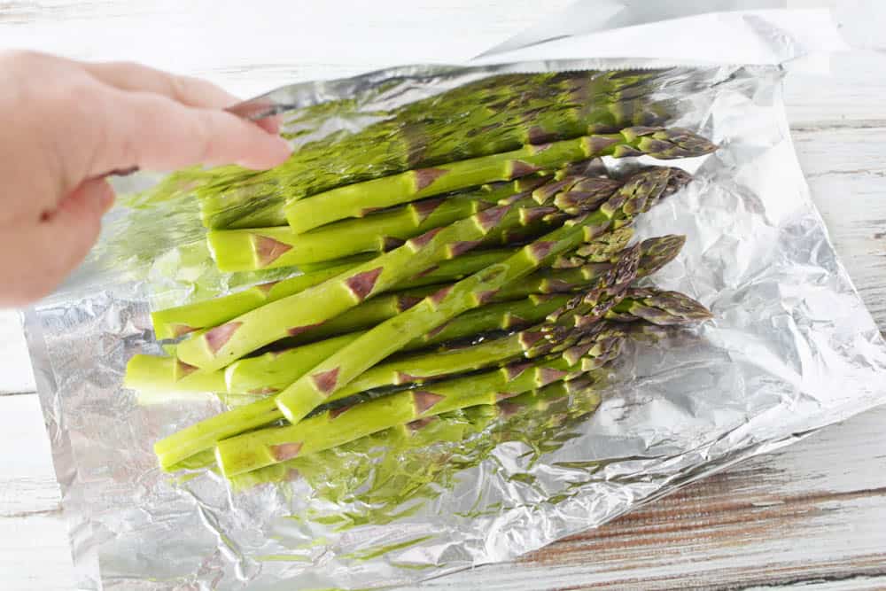 Asparagus on a piece of foil being folded over