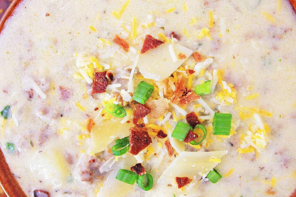 close up of cheeseburger soup with cheese, bacon and green onion toppings