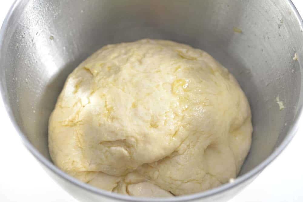 Bread dough in a mixing bowl covered in olive oil