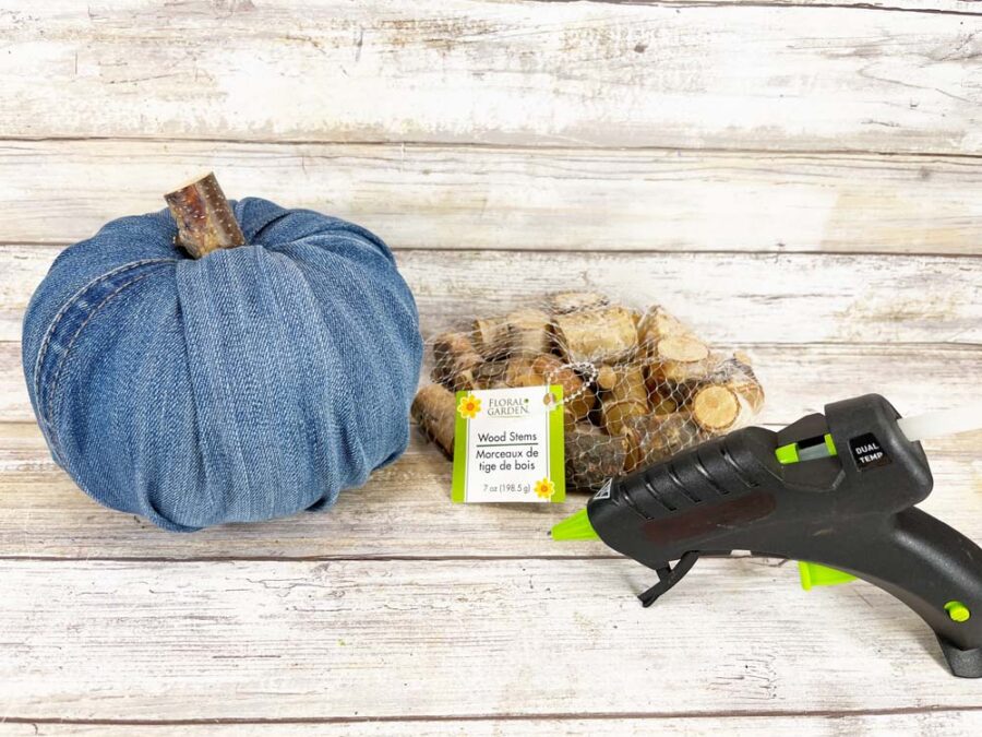 Denim covered pumpkin with bag of wood stems and a hot glue gun