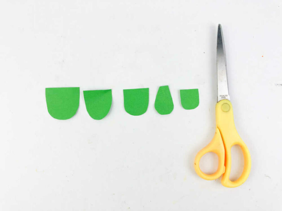 Green paper cut into small arc shapes and scissors
