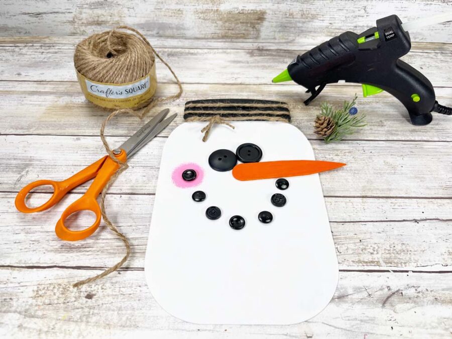 Snowman sign with just twine and a pine bough on the lid