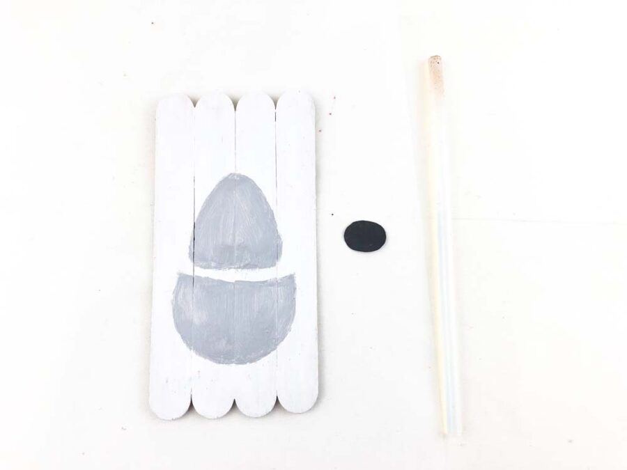 White popsicles sticks with gray paint and a black oval