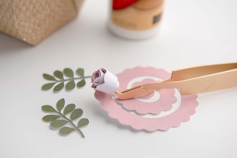 Pink paper flower with tweezers and green paper leaves