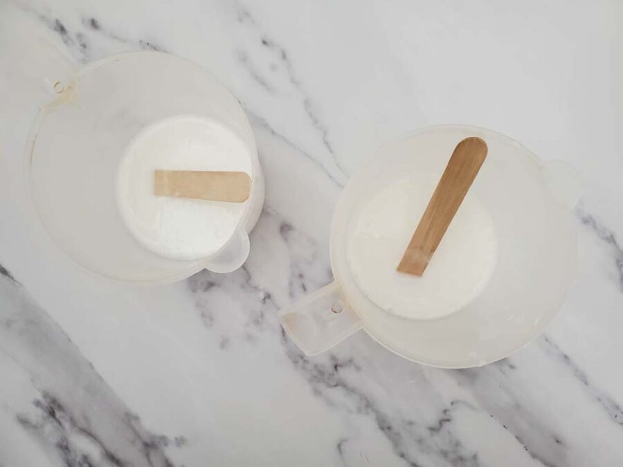 Melted soap base in measuring cups with wooden sticks for stirring