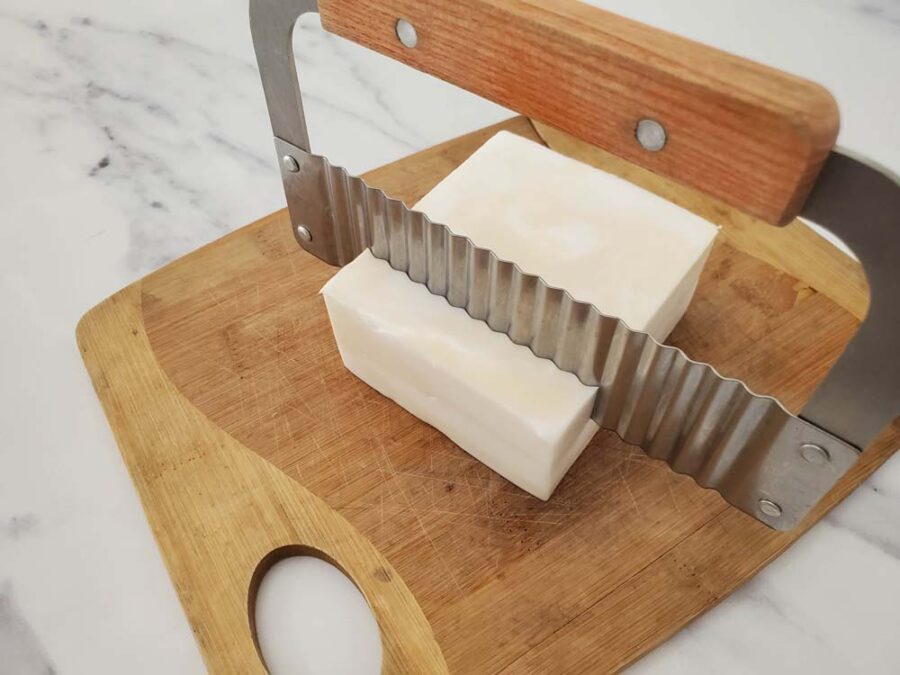 Milk and honey soap being cut with wavy soap cutter