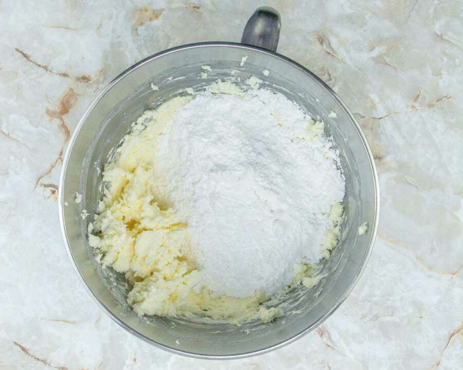 Powdered sugar in a mixing bowl with cream cheese and butter