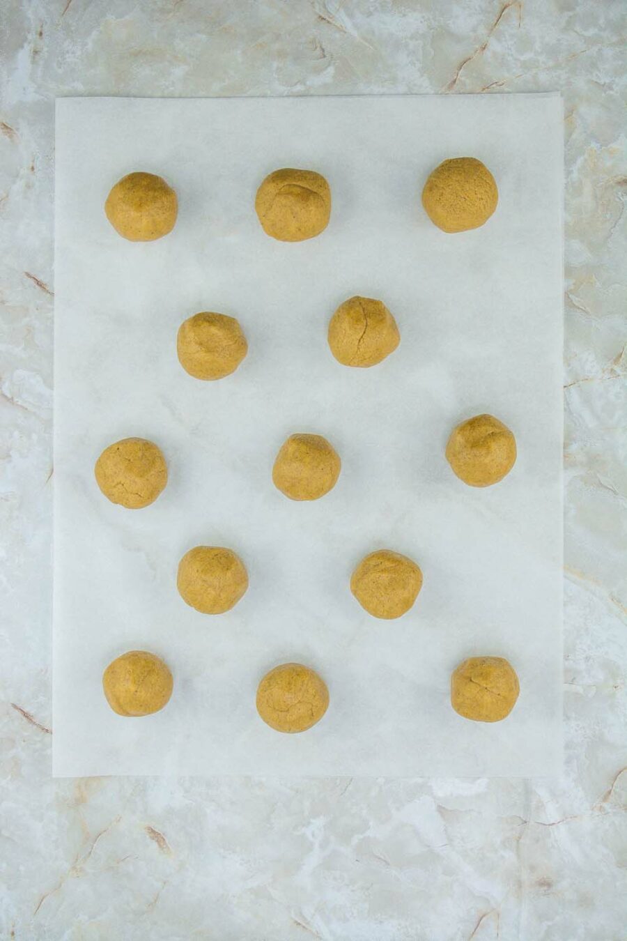 Balls of gingersnap cookie dough on parchment paper