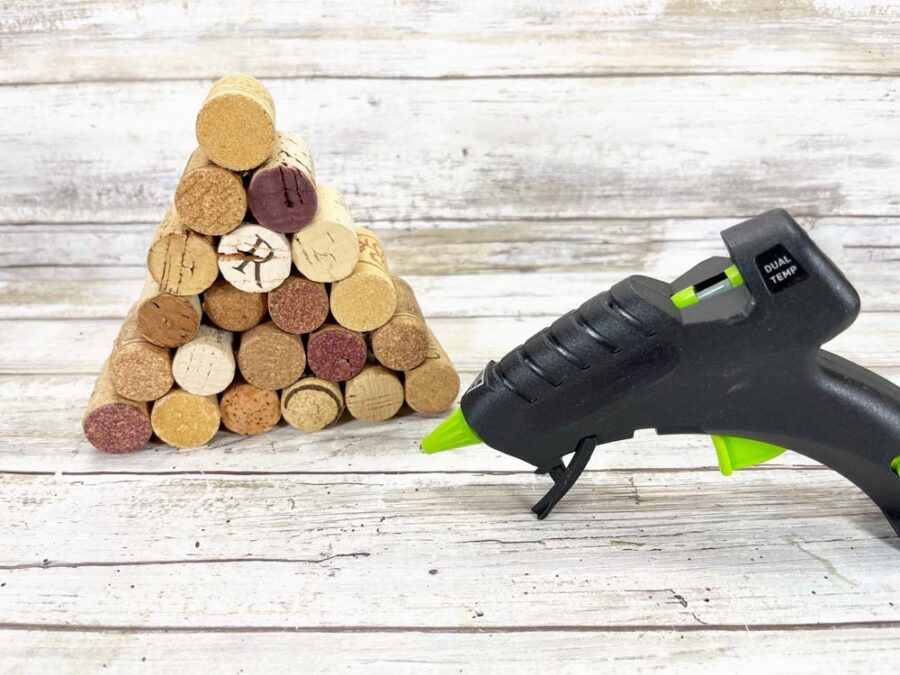 Stacked wine corks in the shape of a triangle next to a glue gun