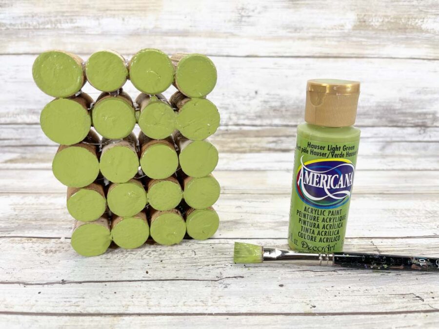 Wine corks in a rectangle with ends painted green, green paint, and a paint brush