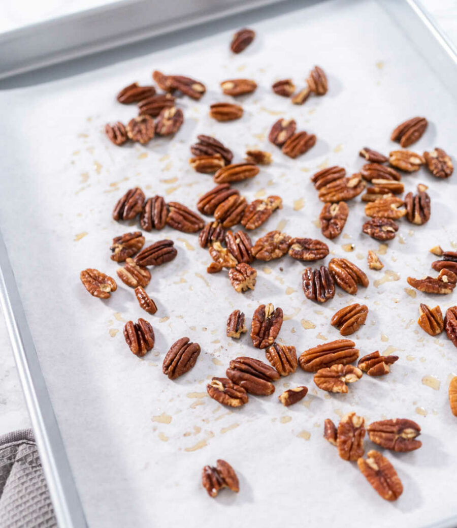 Toasted pecans on a baking sheet lined with parchment paper