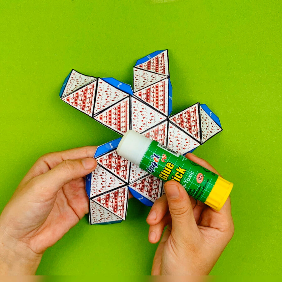 Cut and fold christmas ornament with a person using a glue stick on the tabs.