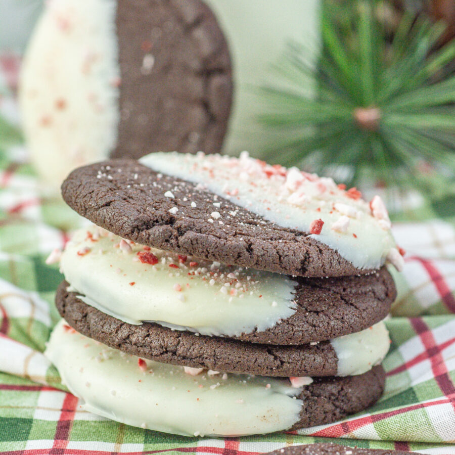 White chocolate dipped chocolate peppermint cookies in a stack on a plaid tablecloth