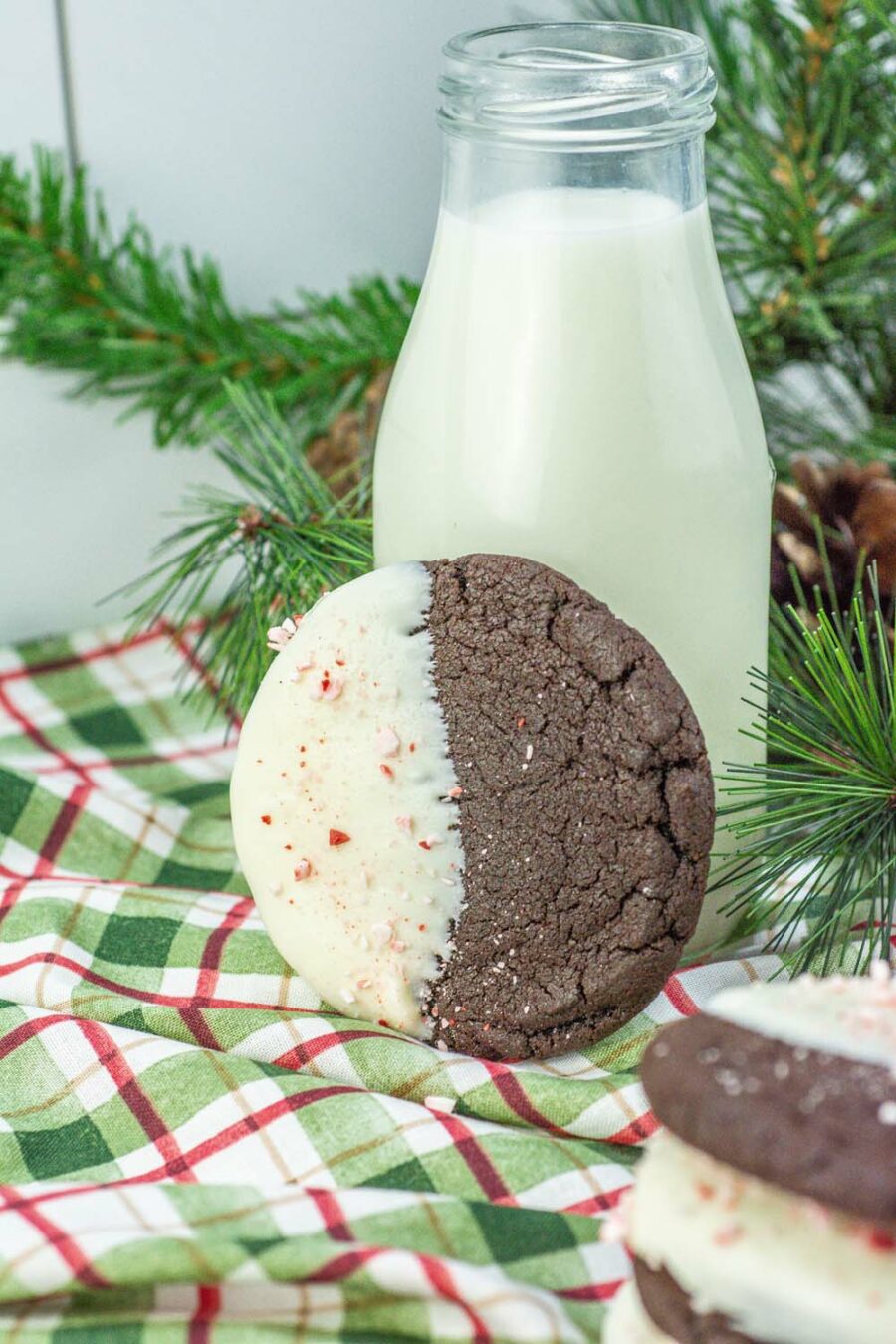 White Chocolate Dipped Chocolate Peppermint Cookie leaning against a small bottle of milk