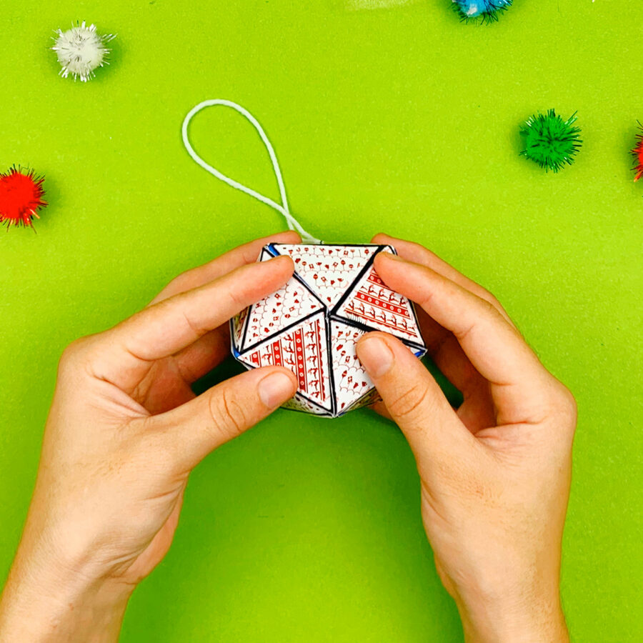A person holding  a print and fold paper Christmas tree ornament craft