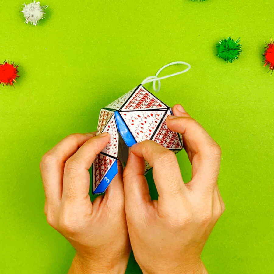 A person folding a print and fold paper Christmas tree ornament craft