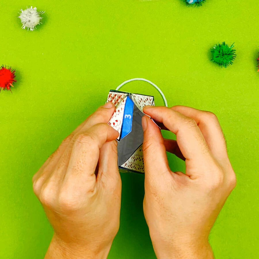 A person gluing tabs of a print and fold paper Christmas tree ornament craft