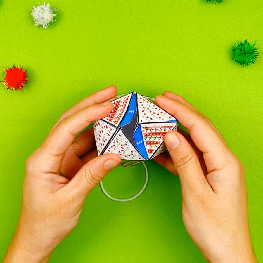 A person completing a print and fold paper Christmas tree ornament craft